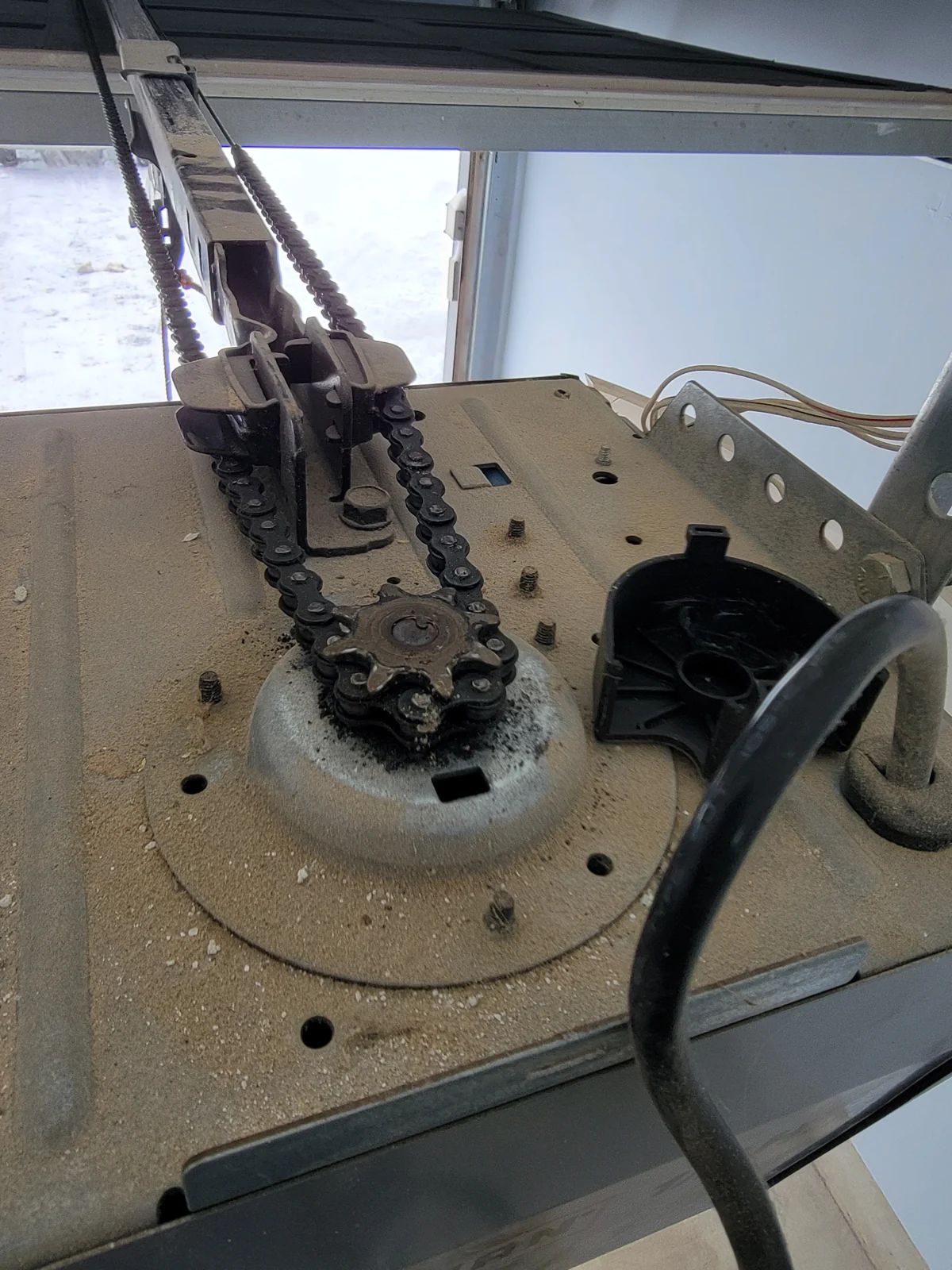 Exposed chain and sprocket mechanism inside a garage door opener.