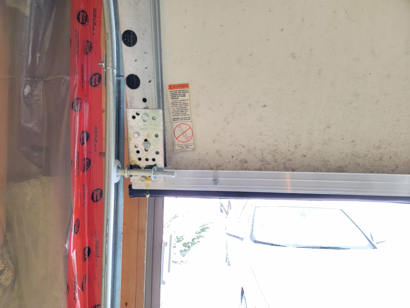 New bottom-retainer extrusion and black weather seal at a garage-door corner.