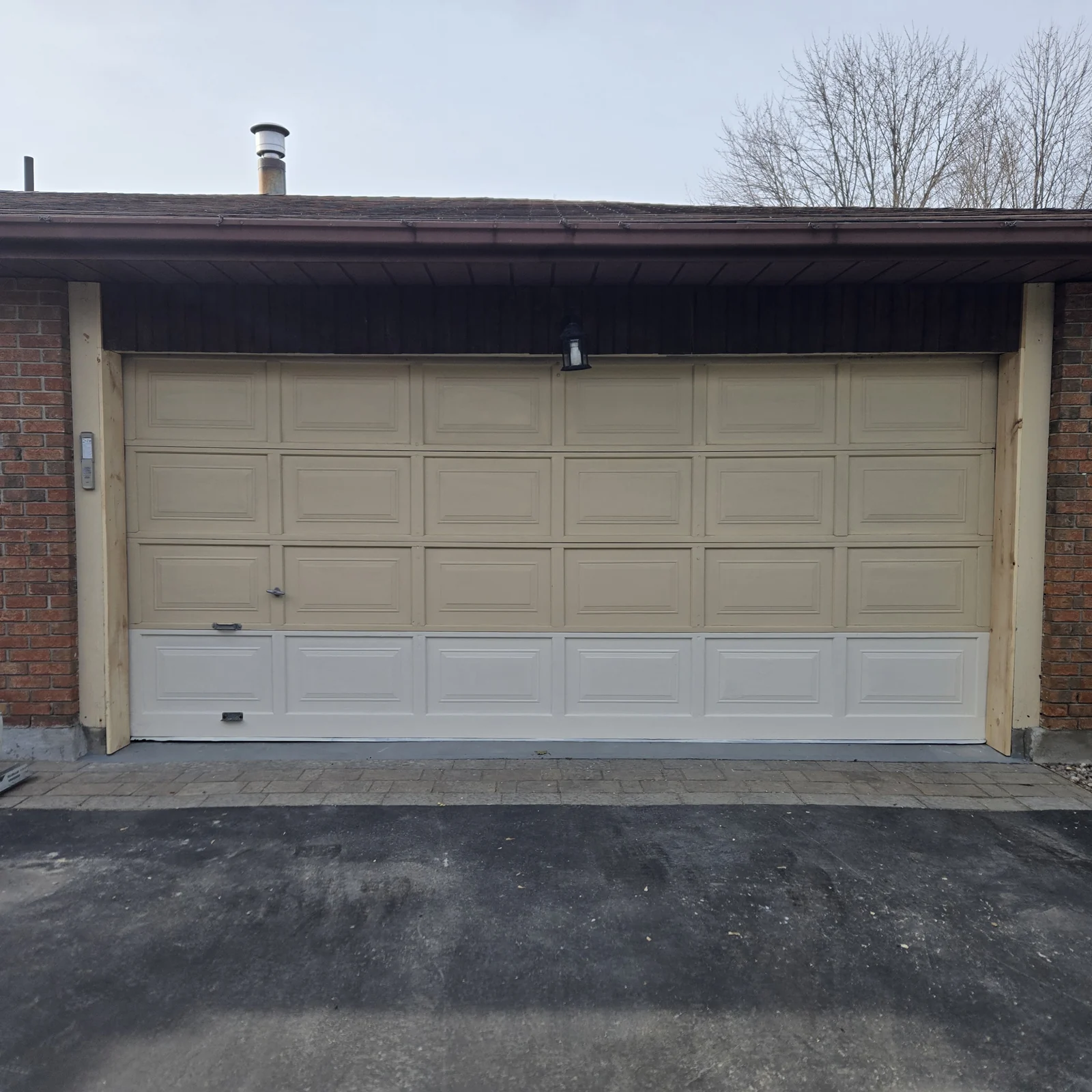 Before: Older double garage door with a mismatched lower section before replacement.