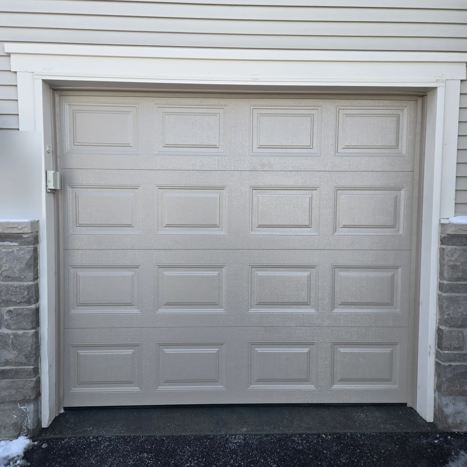 Raised-panel single garage door in a pale neutral finish.