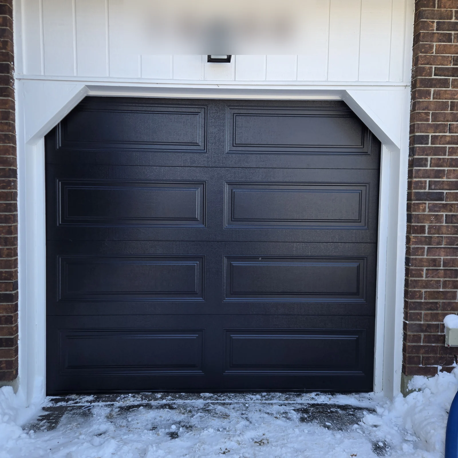 Black raised-panel door inside a light-coloured chamfered surround.