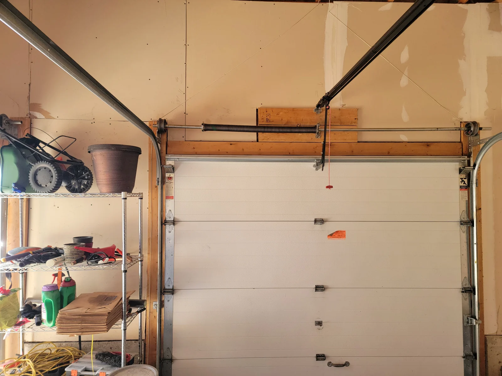 Replacement torsion spring above a white sectional door.