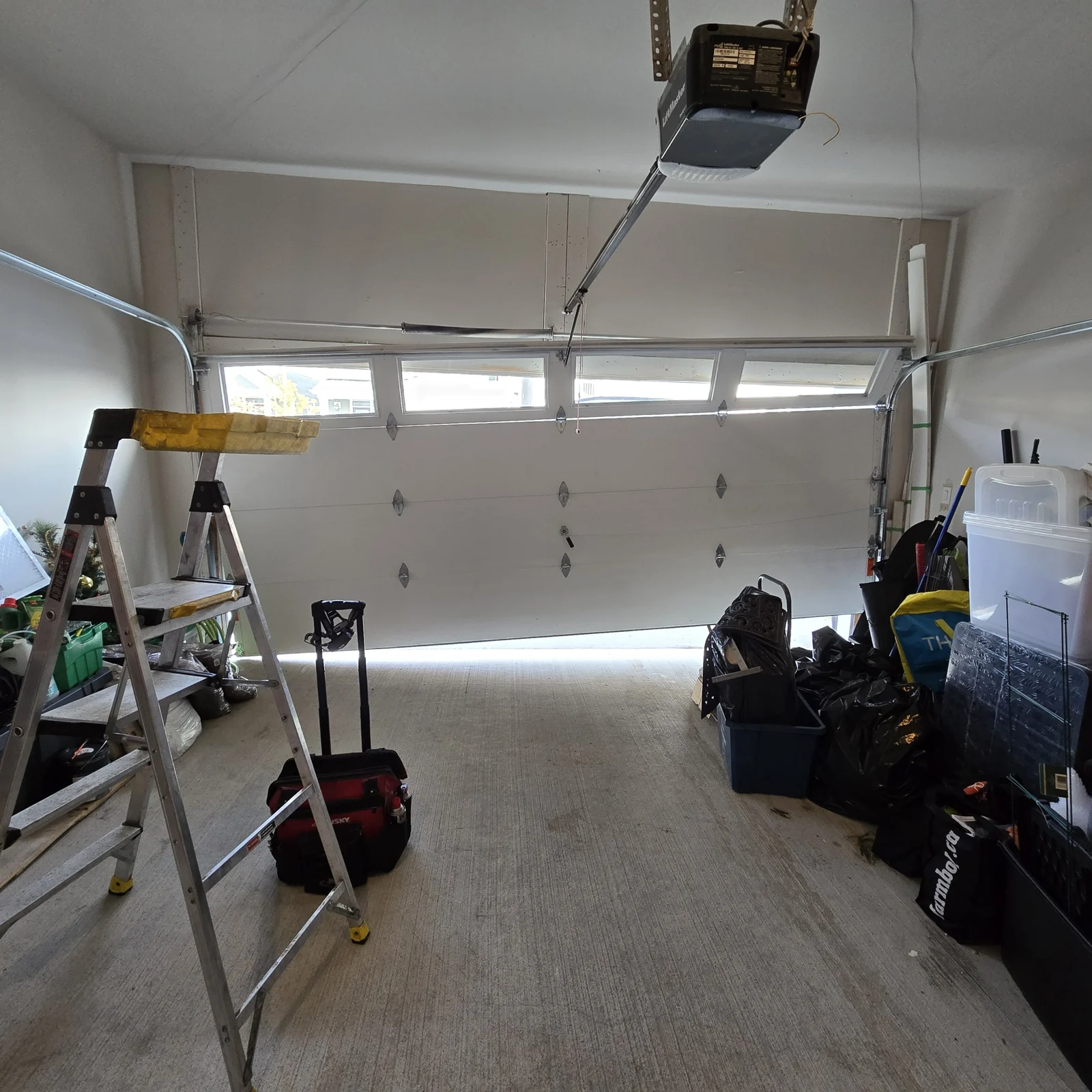 Before: White sectional garage door with its upper section visibly skewed inside a garage.