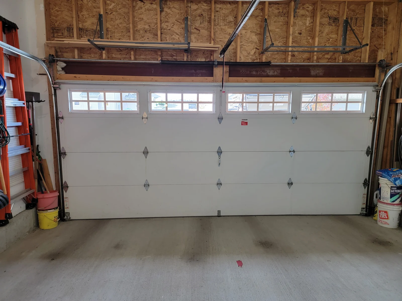 Torsion-spring assembly mounted above the inside of a sectional garage door.