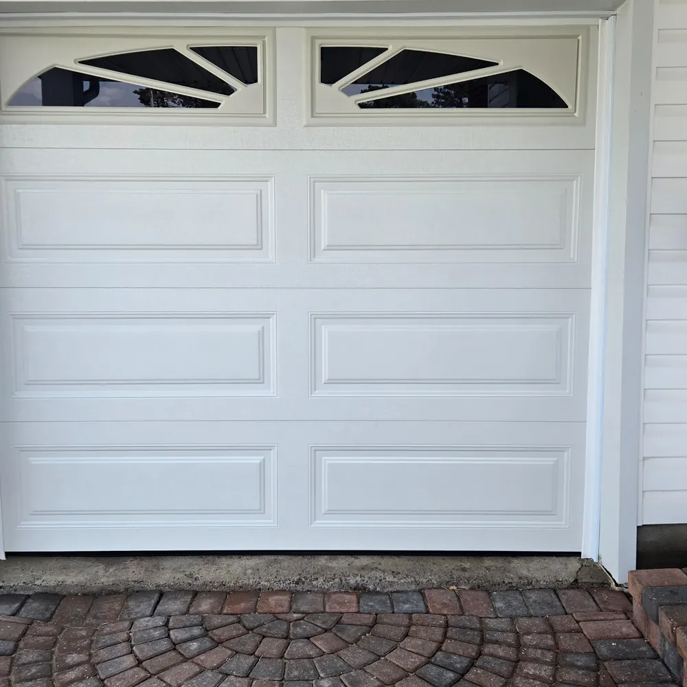 White raised-panel garage door with distinctive geometric top windows.